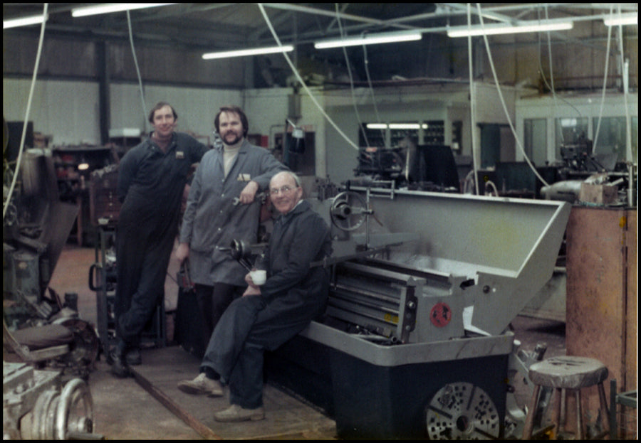 People standing beside precision machining equipment in the historic family factory
